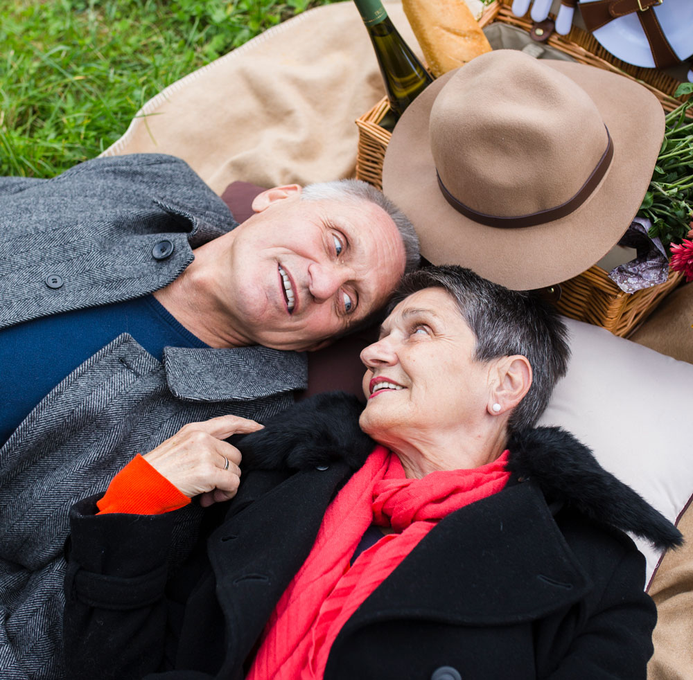 a senior couple laying on the grass together