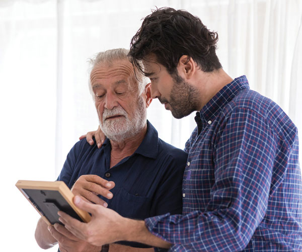 Senior man with son looking at a framed photo